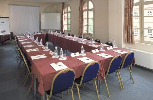 Mercure Albi Bastides في ألبي: صف من الطاولات والكراسي في الغرفة