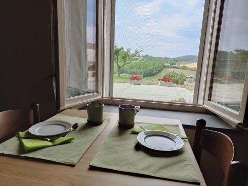 a table with two plates and two cups and a window at Bricco - Bed&Breakfast in Murisengo