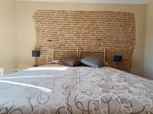a bedroom with a large bed with a brick wall at Bricco - Bed&Breakfast in Murisengo