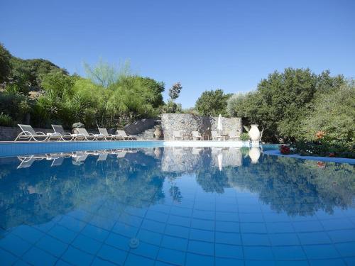 a swimming pool with two chairs and a building at Country Hotel Velani in Avdou