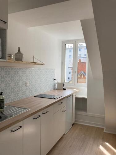 eine Küche mit weißen Schränken und einem Fenster in der Unterkunft Studio neuf Pont-rousseau Rezé in Rezé