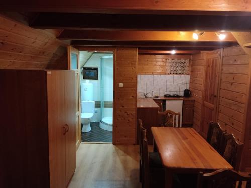 eine Küche und ein Esszimmer mit einem Tisch und einem WC in der Unterkunft Domki Letniskowe Kama 514 - 280 - 102 in Solina