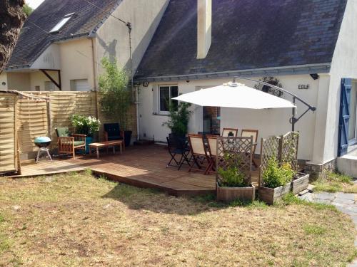 une terrasse en bois avec un parasol dans la cour. dans l'établissement Villa avec Jardin à 250 m de l'océan WIFI, au Pouliguen