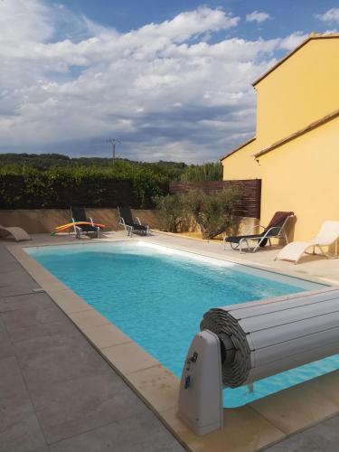 une piscine dans une cour avec des chaises et un bâtiment dans l'établissement VILLA VAI avec piscine, à Vaison-la-Romaine