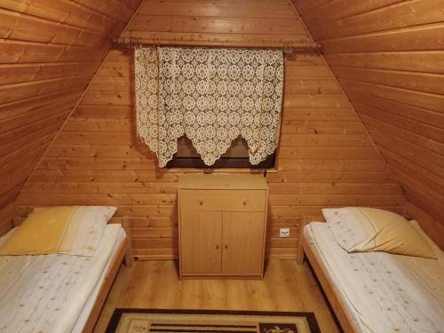 two beds in a wooden room with a window at Domki Letniskowe Kama 514 - 280 - 102 in Solina