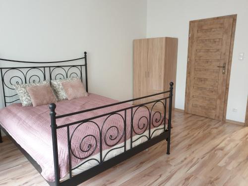 a bedroom with a black metal bed with pink sheets at Apartamenty Dora in Sopot