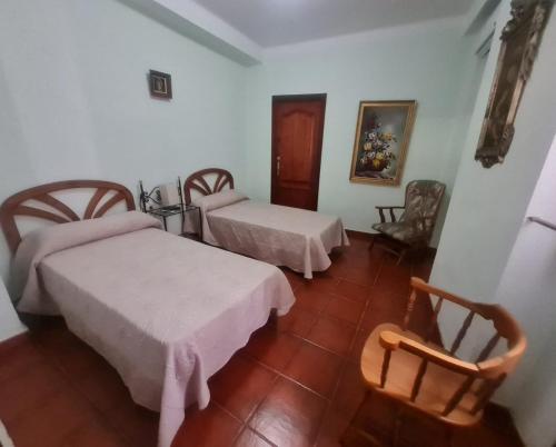 una stanza d'albergo con due letti e una sedia di Casa Rural Los Pequeños (Monserrat) a Monserrat