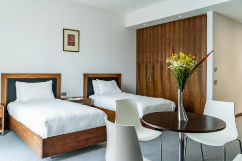 a hotel room with two beds and a table with flowers at Gaya Residences in Shahdag