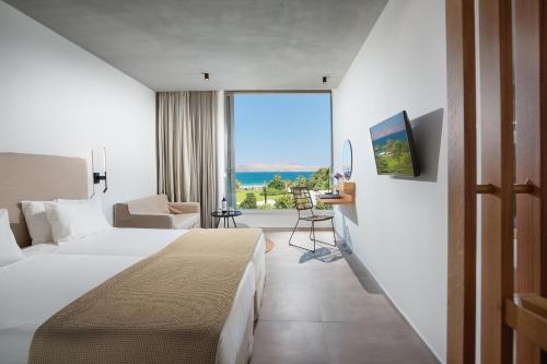 a hotel room with a bed and a large window at Caravia Beach Hotel in Marmari