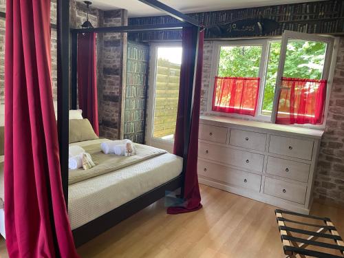 een slaapkamer met een hemelbed en rode gordijnen bij Le Maine N 5 - FLÉAC ANGOULEME - Suite Harry Potter in Fléac