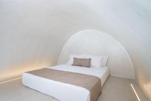 a white bed in a white room with a white ceiling at Alme Luxury Cave Villas in Vóthon