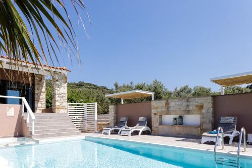 a swimming pool with chairs next to a house at Villa Veni in Kolymvari