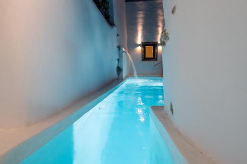 a swimming pool with blue water in a building at Alme Luxury Cave Villas in Vóthon
