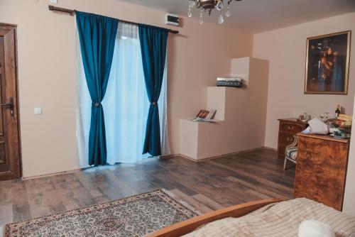 a bedroom with blue curtains and a bed and a desk at Villa 1880 in Sremski Karlovci