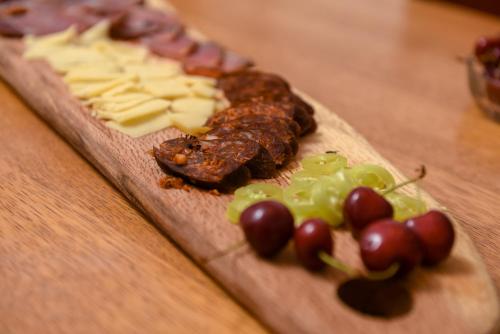 a wooden cutting board with meat and cheese and grapes at Villa 1880 in Sremski Karlovci