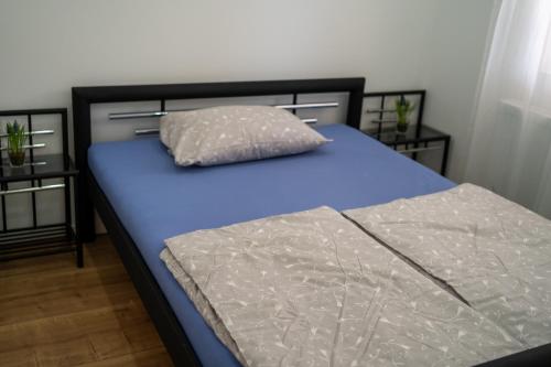 a bed with blue sheets and a pillow on it at Pension Ahnatal in Weimar