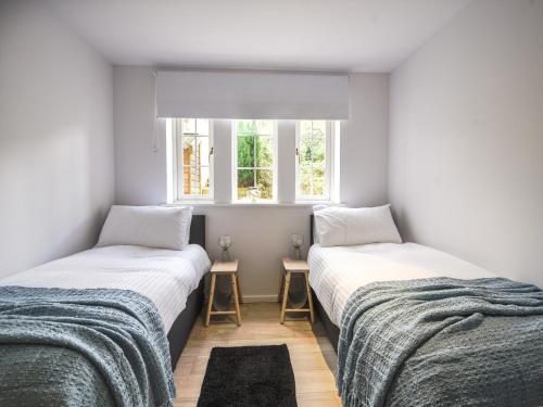 two beds in a room with white walls and a window at 1 Buckfields in Lyme Regis