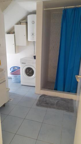 a bathroom with a washing machine and a blue shower curtain at Rustic Holiday Home Miketa in Lukoran