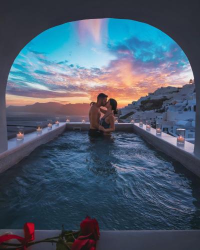 a man and a woman sitting in a swimming pool at Echoes Luxury Suites in Oia
