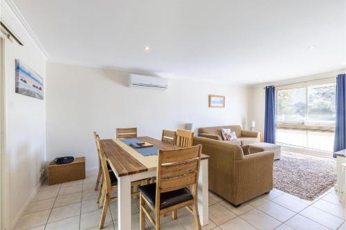 a living room with a dining room table and a couch at Happy Tails pet friendly air conditioned in Corlette
