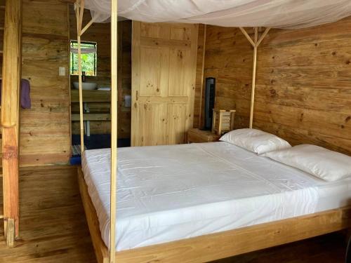 a bedroom with a canopy bed with wooden walls at Bungalows Baobab in San Isidro de El General