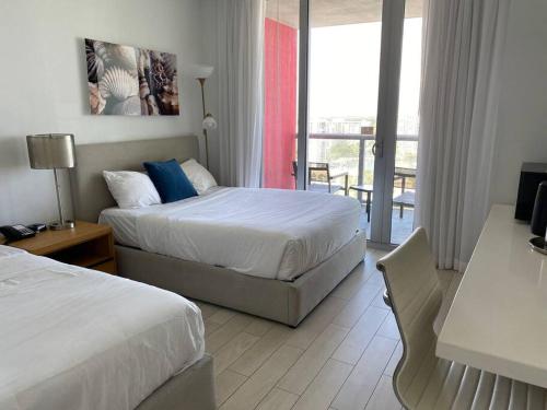 a hotel room with two beds and a balcony at Sunlit BeachWalk Studio 2 Full Beds Coastal Charm -26B in Hallandale Beach