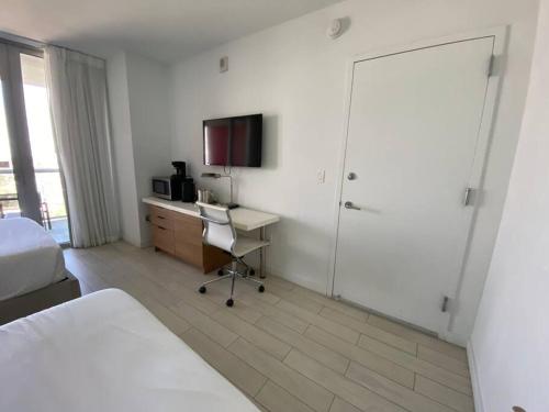 a bedroom with a bed and a desk with a television at Sunlit BeachWalk Studio 2 Full Beds Coastal Charm -26B in Hallandale Beach
