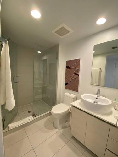 a bathroom with a toilet and a sink and a shower at Sunlit BeachWalk Studio 2 Full Beds Coastal Charm -26B in Hallandale Beach