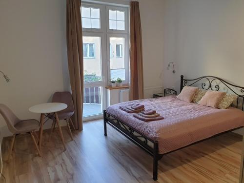 a bedroom with a bed and a table and a window at Apartamenty Dora in Sopot