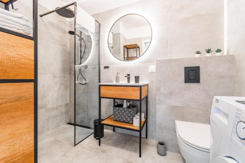 een badkamer met een douche, een wastafel en een spiegel bij Apartamenty NCNK Osiedle Bursztynowe w Jantarze in Jantar