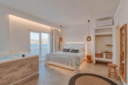 um quarto branco com uma cama e uma banheira em Nautica Suites-Superior Seaview suite with jacuzzi em Antiparos Town