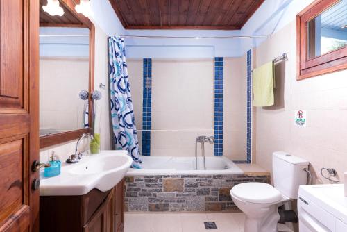 a bathroom with a tub and a toilet and a sink at Sarakinas Residences in Myrtos