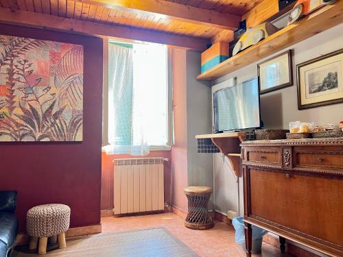sala de estar con TV, mesa y ventana en B&B Borgo, en Ventimiglia