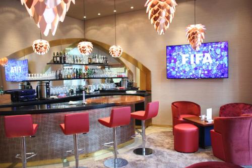 a bar with red chairs and a tv on the wall at Top Hotel Hammer - Mainz Hauptbahnhof in Mainz
