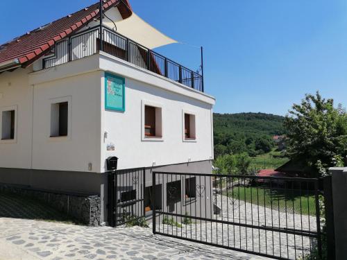 a white building with a black fence in front of it at Szigligeti Mandula Kert Vendégház in Szigliget