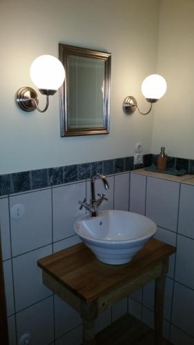a bathroom with a sink with two lights and a mirror at Ferienwohnungen Bistro Tebecks in Wadern