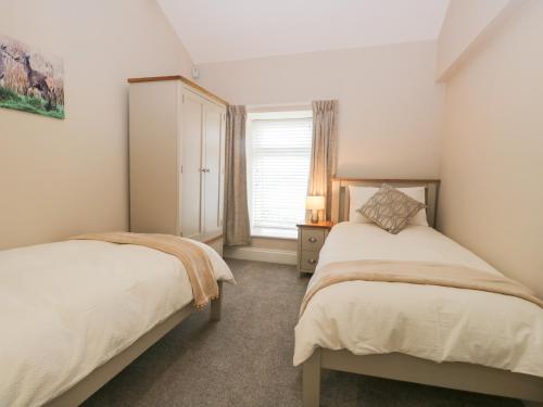 a bedroom with two beds and a window at Oxen Park Farm Cottage in Ulverston