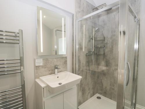 a white bathroom with a sink and a shower at Oxen Park Farm Cottage in Ulverston