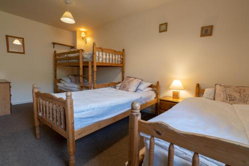 a bedroom with two beds and a bunk bed at The Holmes Barn - Sleeps 16 - Peak district in Buxton