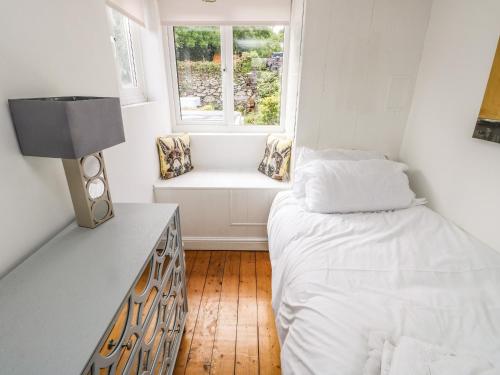 Habitación pequeña con cama y ventana en Y Bwthyn Bach, en Bangor
