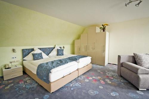 a bedroom with a bed and a chair and a couch at Hotel Waldrausch in Hahnenklee-Bockswiese