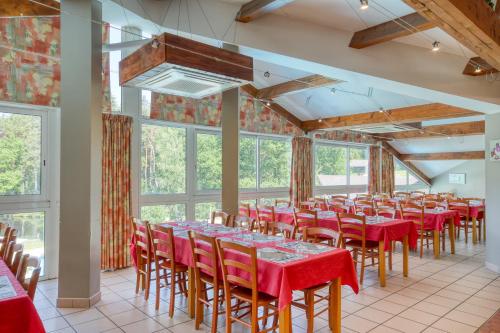 une chambre avec des tables et des chaises dans une chambre avec des fenêtres dans l'établissement VVF Corrèze Pays d'Eygurande, à Eygurande