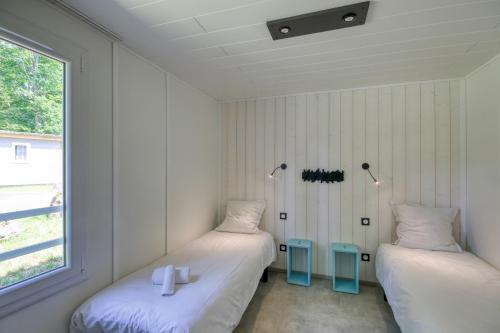 zwei Einzelbetten in einem Zimmer mit Fenster in der Unterkunft VVF Corrèze Pays d'Eygurande in Eygurande
