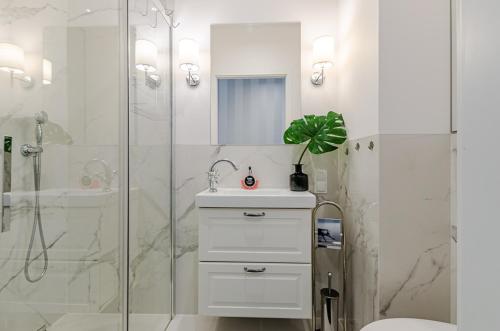a white bathroom with a sink and a shower at Nowoczesny apartament na 8 osób na Starówce in Gdańsk