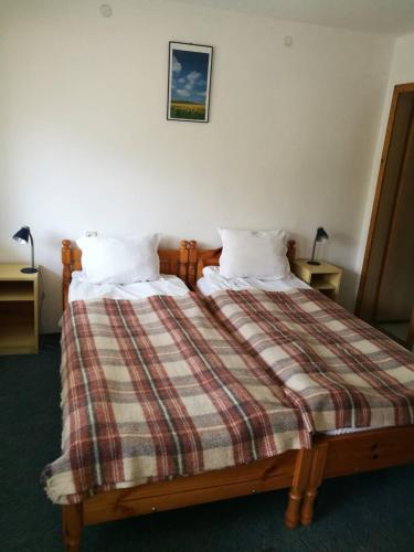a bedroom with a bed with a plaid blanket at Самостоятелни стаи в къща за гости Балкан in Ribarica