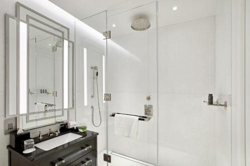 a white bathroom with a shower and a sink at Four Seasons Hotel London at Tower Bridge in London