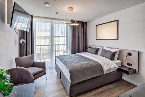 a bedroom with a large bed and a chair at MOOI Apartments Schlieren in Schlieren