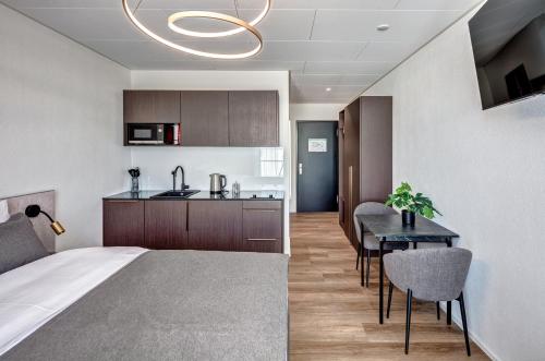 a bedroom with a bed and a kitchen with a table at MOOI Apartments Schlieren in Schlieren