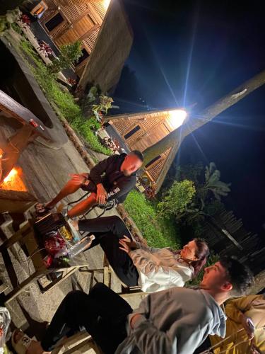 a group of men sitting on a sidewalk at night at Triangle House and hot spring in Kintamani