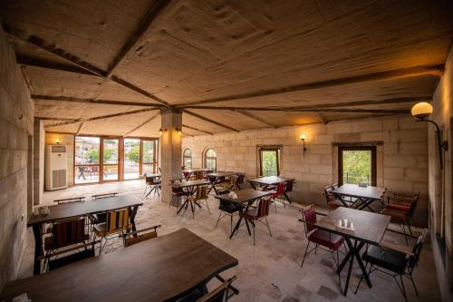 a large room with tables and chairs and windows at Ahiyan Hotel in Uçhisar